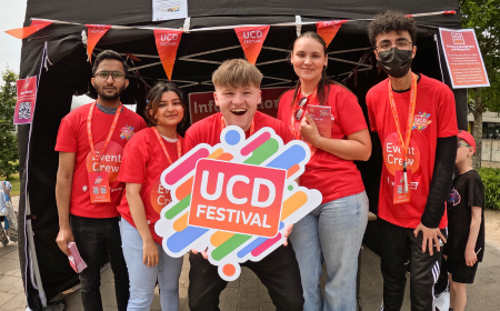 Five UCD Festival volunteers wearing red crew t-shirts, smiling at the camera.